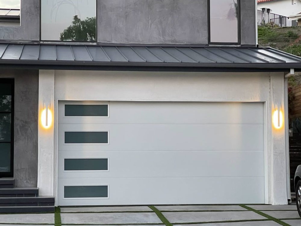 A white flush panel residential garage door with side frosted windows. The door has 2 lights on the side.